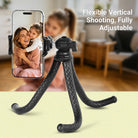 Flexible phone tripod with smartphone displaying a mother and child, set against a blurred indoor background.